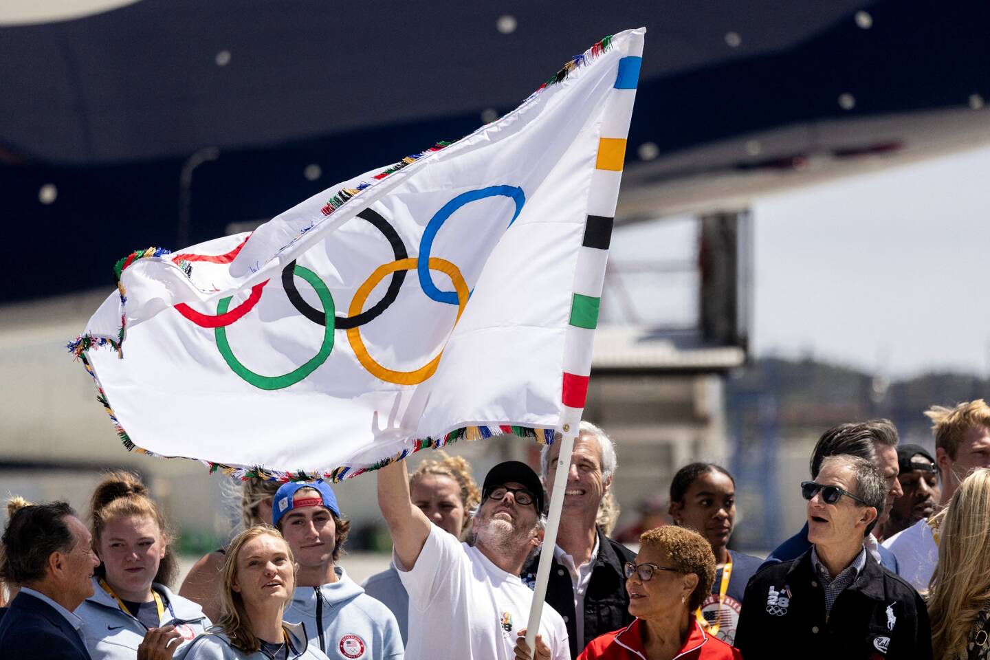 Des athlètes et des officiels célébrant l'arrivée du drapeau olympique à Los Angeles le 12 août 2024. 