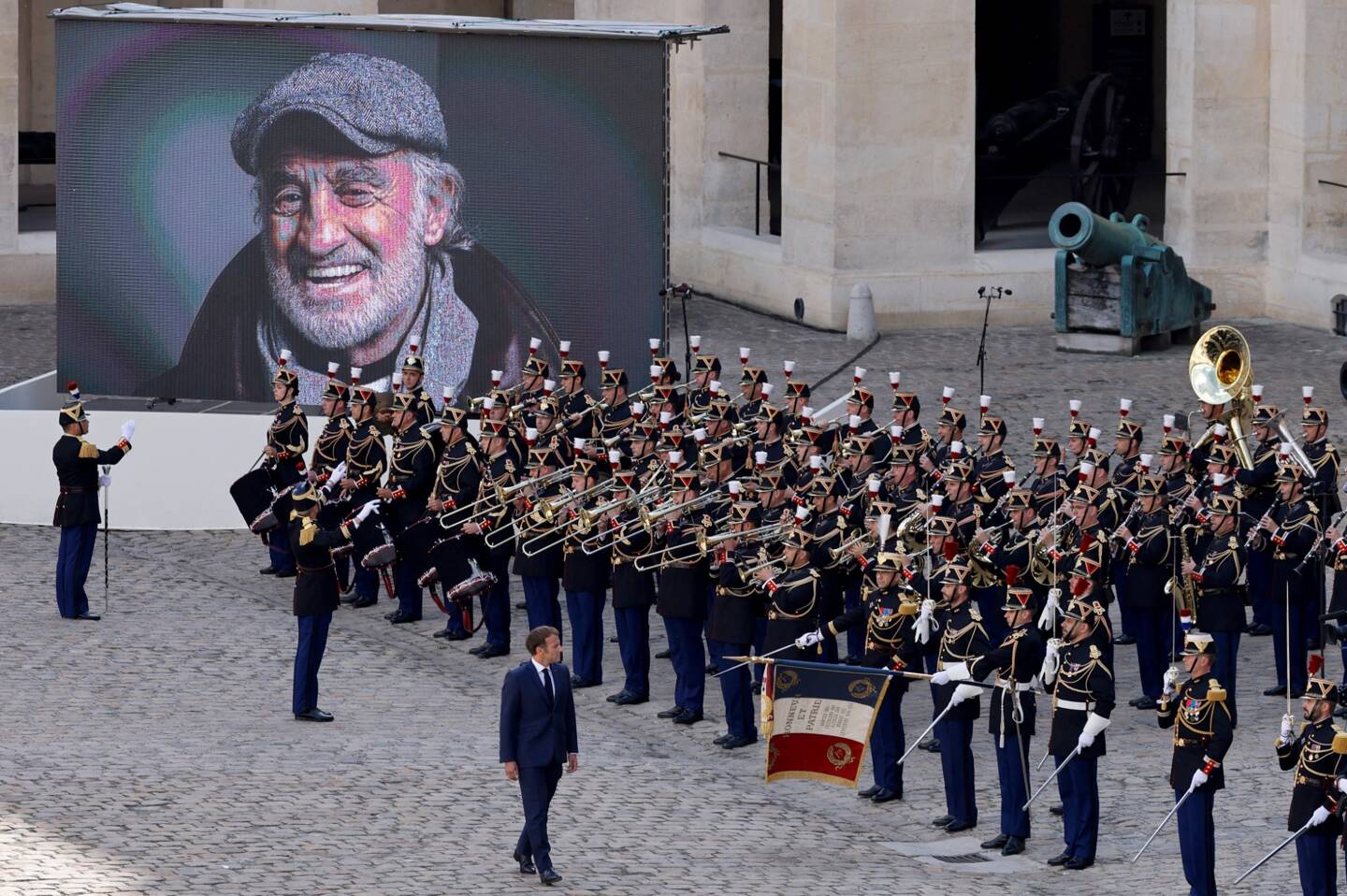 Emmanuel Macron, passant les troupes en revue, devant le sourire inoubliable de Belmondo. 