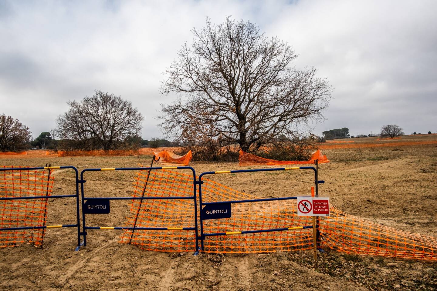 Vue sur le chantier de construction du parcours de golf de la Raho, délimité par un filet orange et des panneaux interdits dans le village de Villeneuve de la Raho, dans le département des Pyrénées-Orientales, dans le sud de la France, le 15 février 2024.