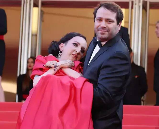 En fauteuil roulant, la styliste Lucie Carrasco gravit les marches du palais des Festivals dans les bras de son mari