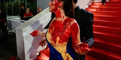 Une femme vêtue aux couleurs de l'Ukraine se recouvre de faux sang sur le tapis rouge de Cannes, les images