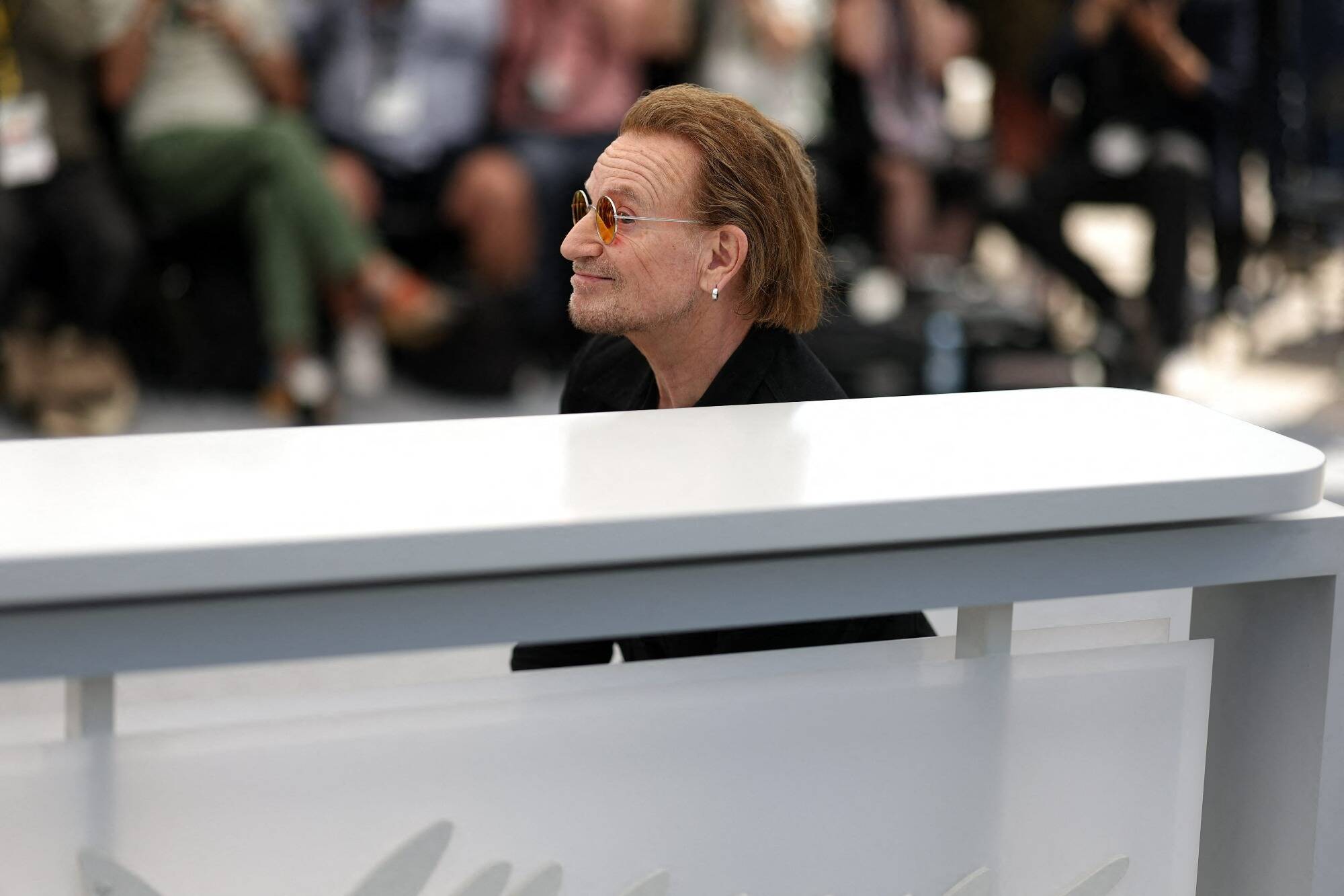 Allongé, saluant la foule... Le show de Bono devant les photographes au photocall de "Bono: Stories of surrender"