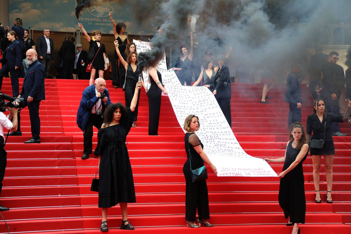 Vêtues de noir, les militantes ont pris la pose, le poing levé, avant d'utiliser des fumigènes, nimbant le tapis rouge de fumée noire.