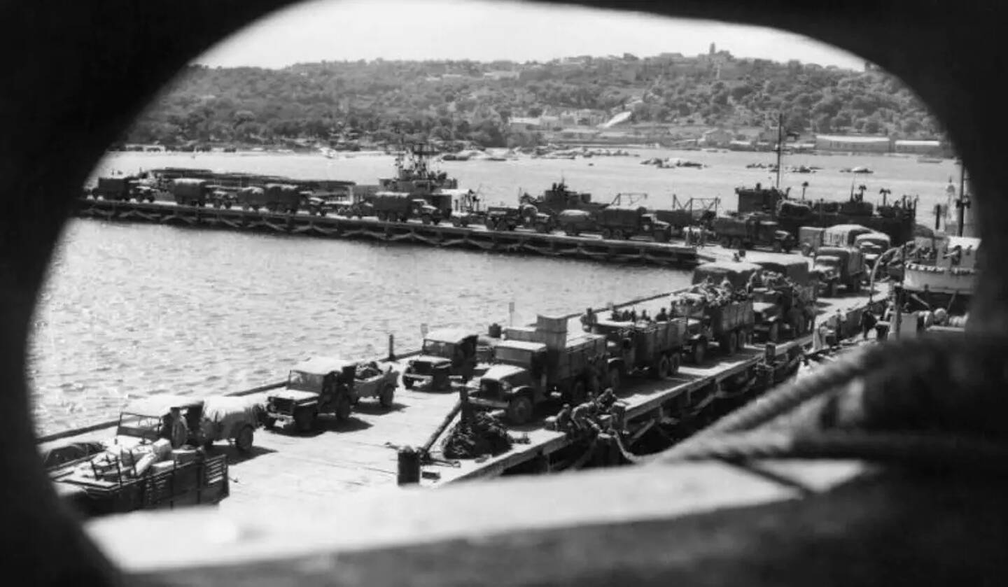 Reproduction d'une photographie réalisée en 1943 montrant des véhicules et du matériel militaire américains débarquant au port de Porto-Vecchio, en Corse-du-Sud.