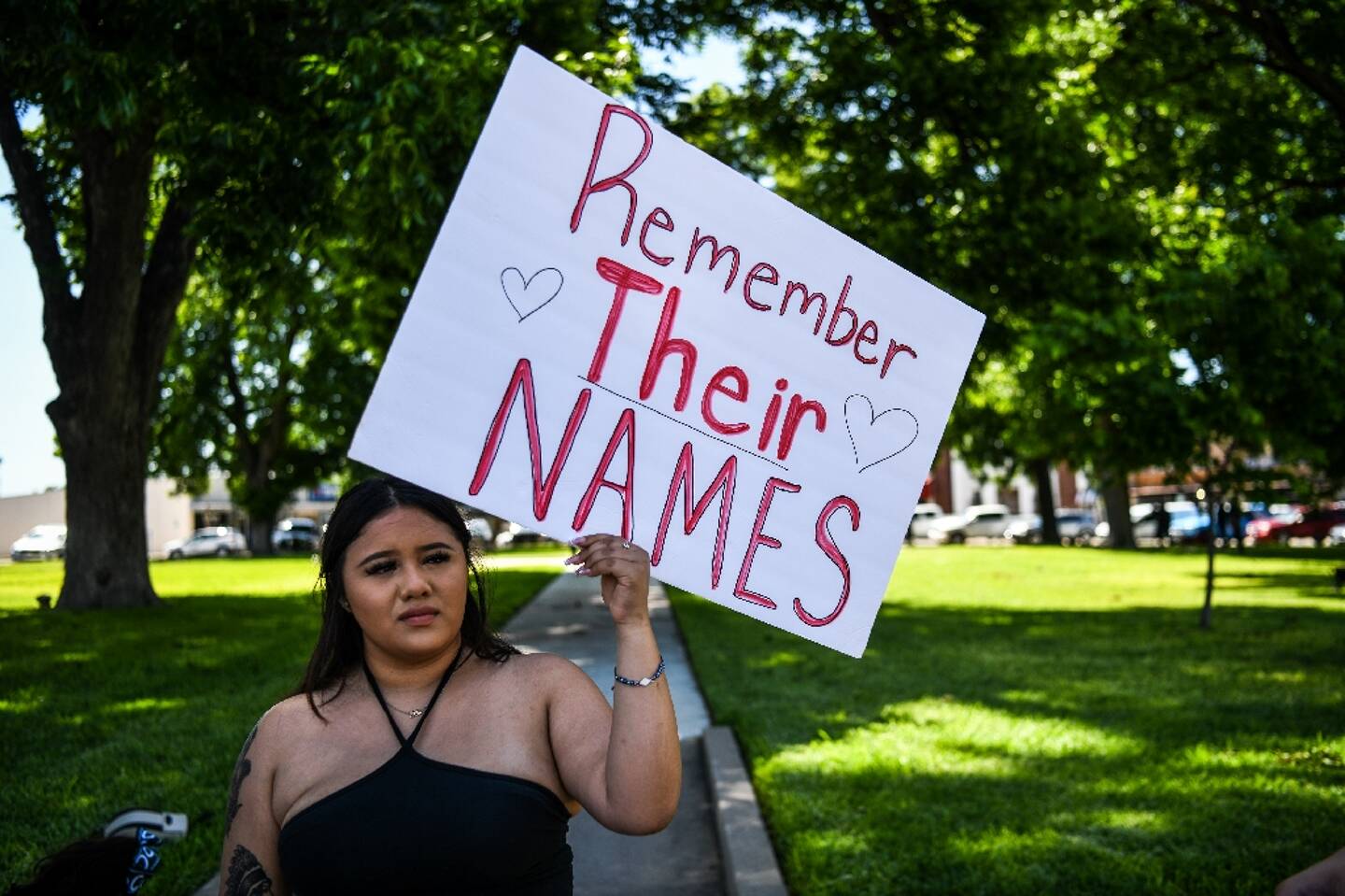 Une femme tient une pancarte  où est inscrit "souvenez-vous de leurs noms", à Uvalde (Texas), le 25 mai 2022