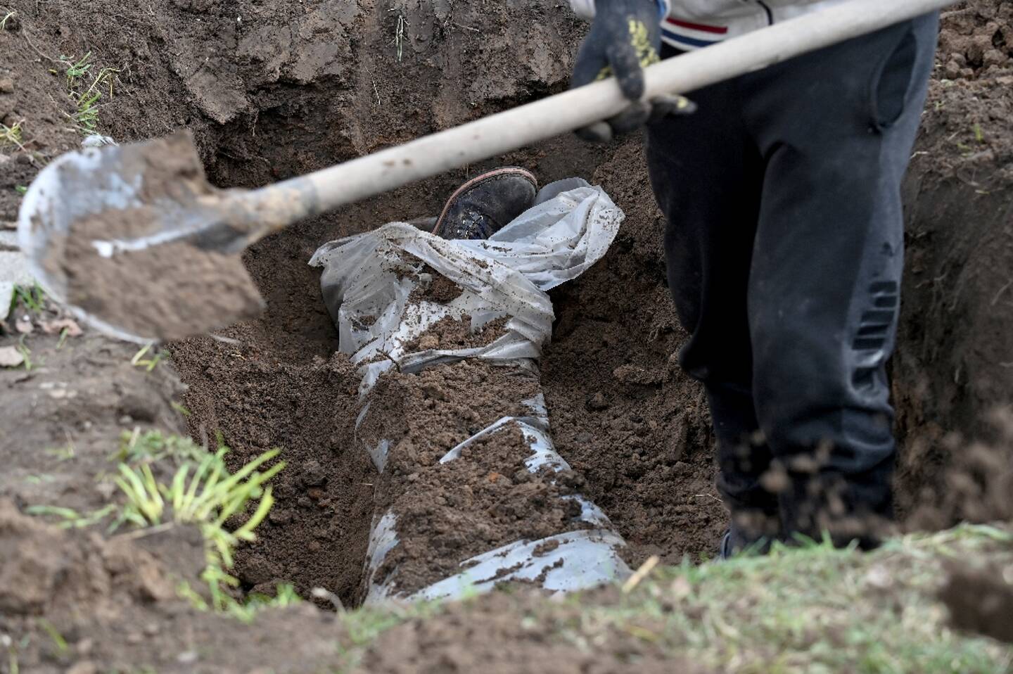 A municipal employee digs up the body of a victim in Andriivka, near Kiev, on April 11, 2022 in Ukraine.