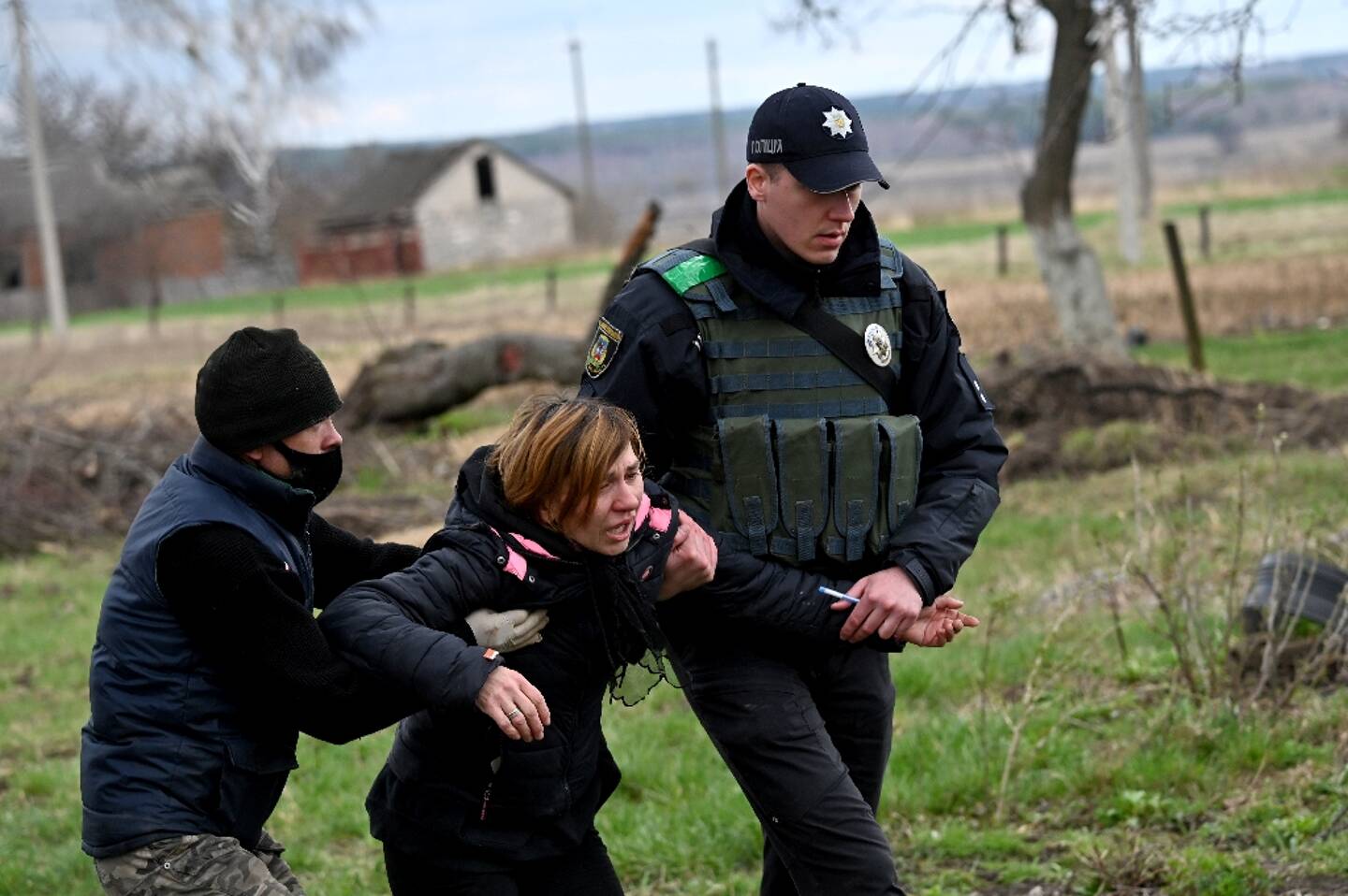 A woman supported by police during the exhumation of the body of her slain husband in Andriïvka, near Kyiv, on April 11, 2022 in Ukraine.