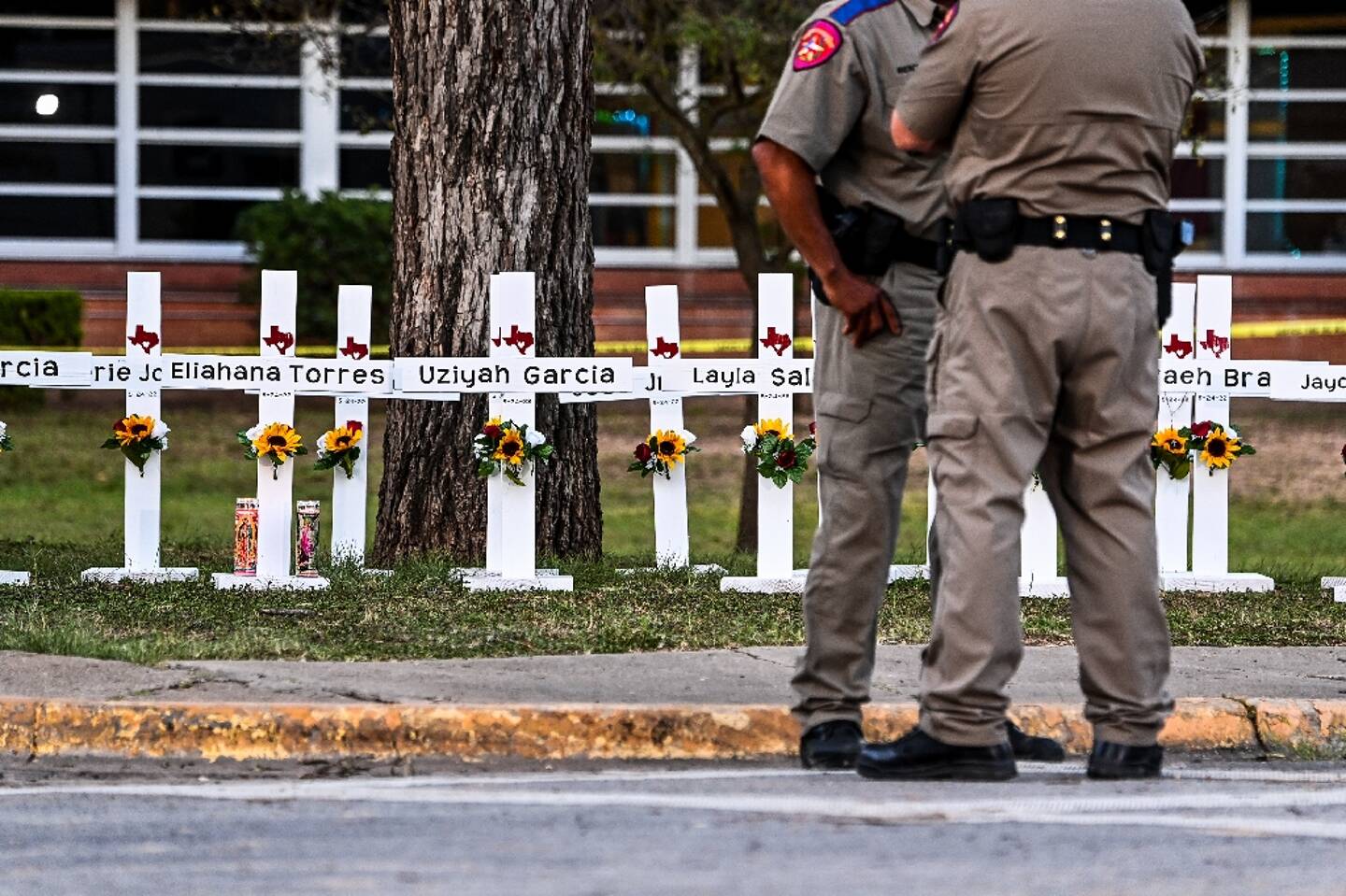 Des policiers se tiennent le 26 mai 2022 devant un mémorial de fortune pour les victimes de la fusillade dans l'école primaire Robb d'Uvalde au Texas
