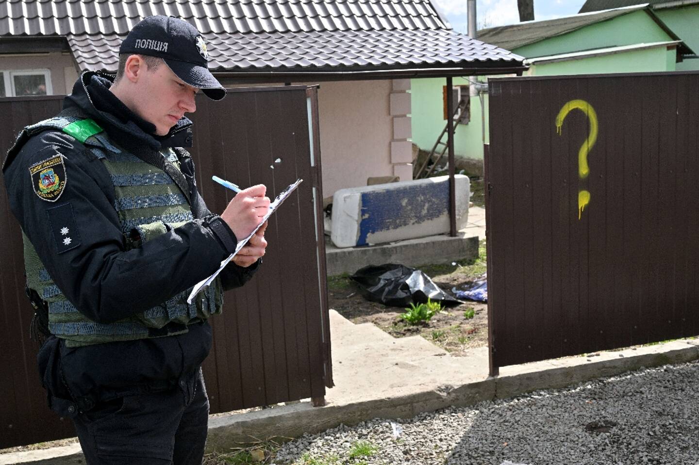 A police officer fills in a file during the excavation of the victims in Andriivka, near Kiev, on April 11, 2022 in Ukraine.