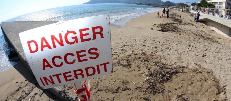 Sur les plages quasi désertes de Cannes, un panneau met en garde les baigneurs. 	