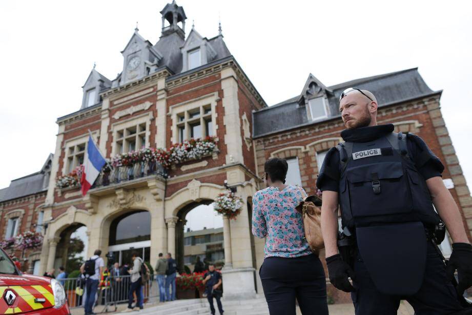 A French police officer stands guard by Saint-Etienne-du-Rouvray's city hall following a hostage-taking at a church in Saint-Etienne-du-Rouvray, northern France, on July 26, 2016 that left the priest dead.A priest was killed on July 26 when men armed with knives seized hostages at a church near the northern French city of Rouen, a police source said. Police said they killed two hostage-takers in the attack in the Normandy town of Saint-Etienne-du-Rouvray, 125 kilometres (77 miles) north of Paris. / AFP PHOTO / CHARLY TRIBALLEAU FRANCE-ATTACK-CHURCH-HOSTAGE