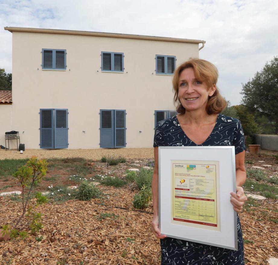 Sophie Bidart devant sa maison, avec le label Maison passive premium.	