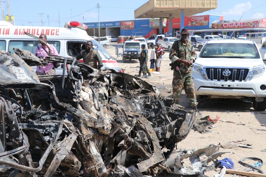 Un soldat se tient près de la carcasse d'une voiture détruite par un attentat qu a fait au moins 76 morts le 28 décembre 2019 à Mogadiscio.
